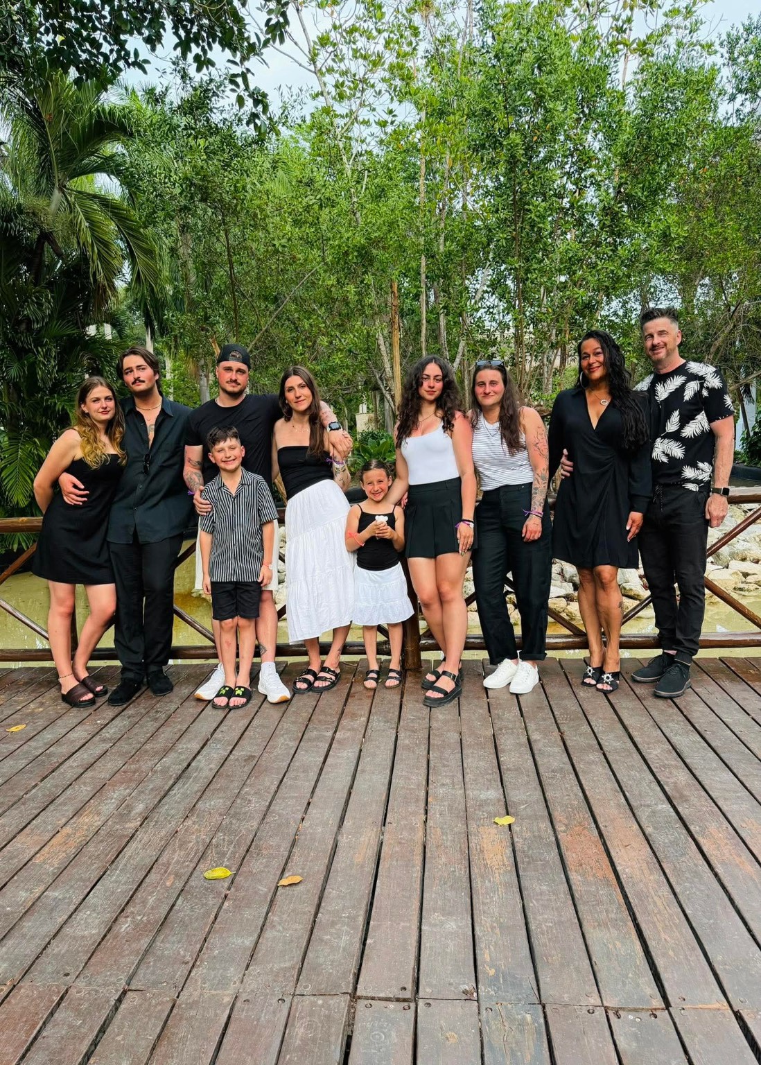 Multi-generational family of ten posing together on a wooden bridge at Grand Riviera Princess Family Club in Riviera Maya during their all-inclusive vacation.